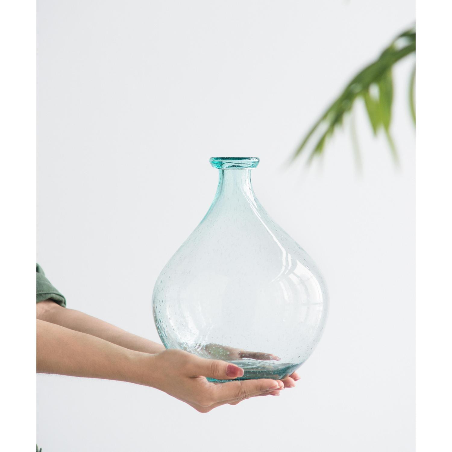 Light blue glass vase in a woman’s hand