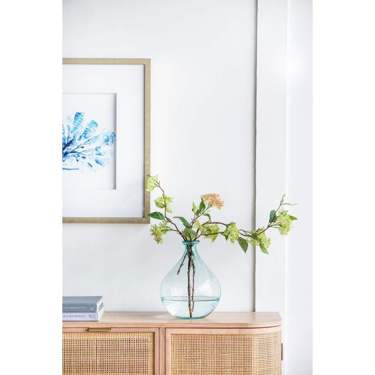 Blue glass vase filled with water and flowers on wood cabinet