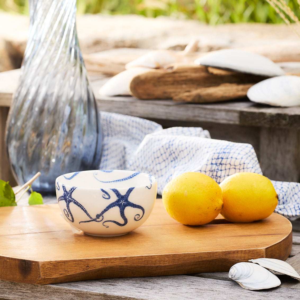 Blue Starfish Snack Bowl on a wooden serving board beside lemons, patterned linen, and a blue glass vase