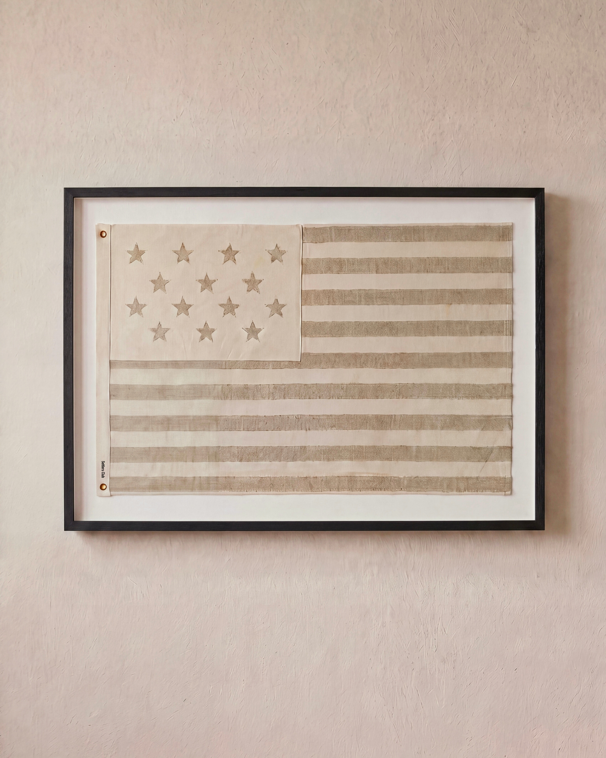 Sand-toned embroidered American flag displayed horizontally in a black shadowbox frame.