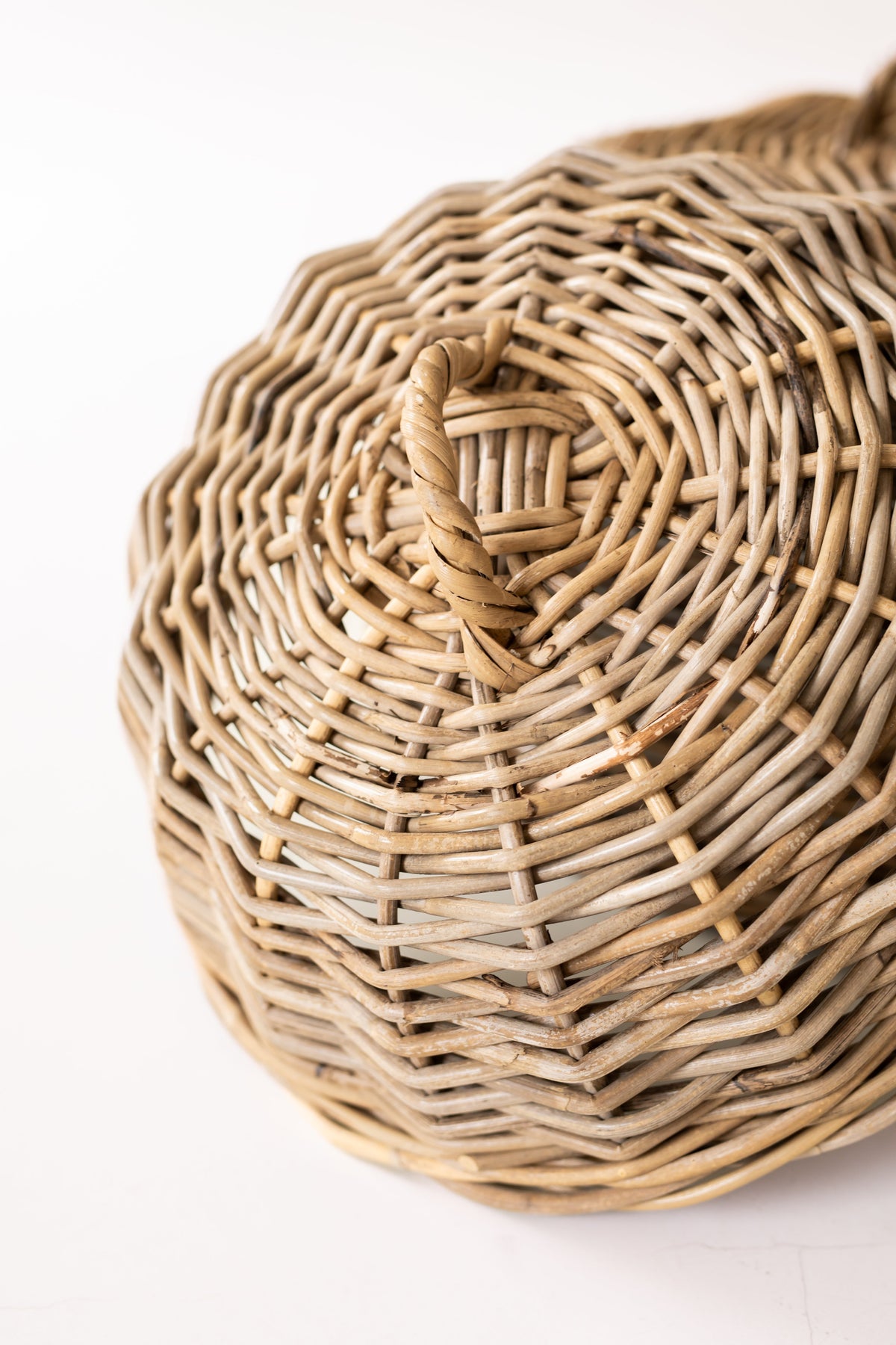 Detail of a rattan cloche’s top loop handle and circular weave