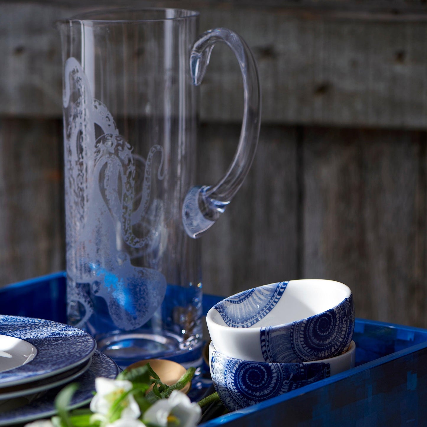 a blue and white table setting with a glass pitcher