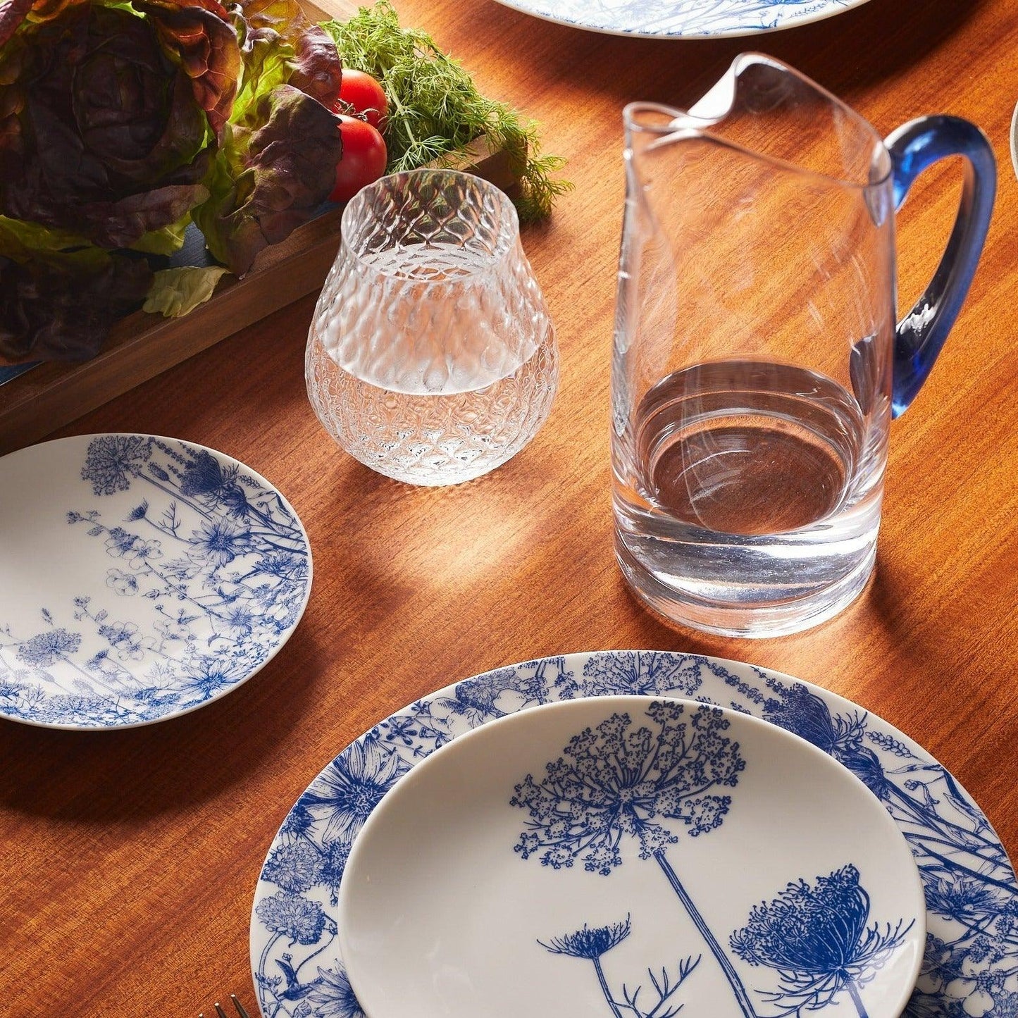 a wooden table topped with blue and white plates