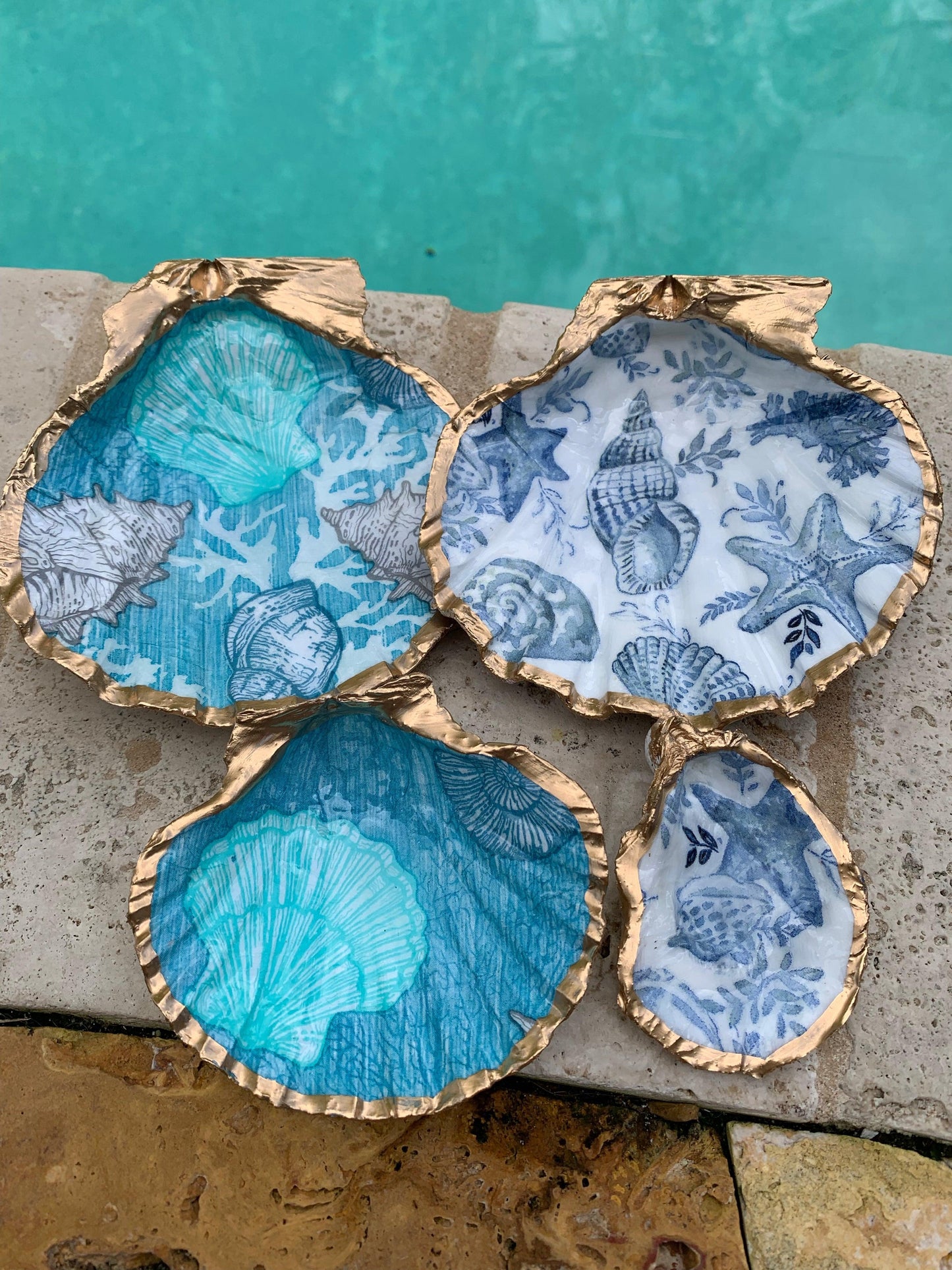 Four gold painted shells with blue designs