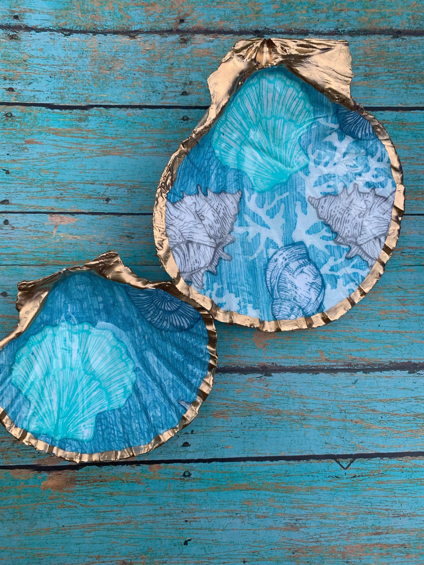 Two gold shells with blue painted designs