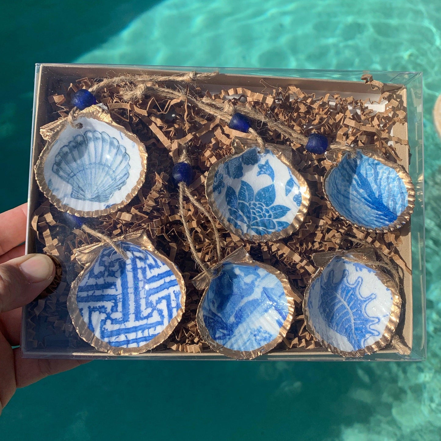 Six mini shells painted blue and white in a box