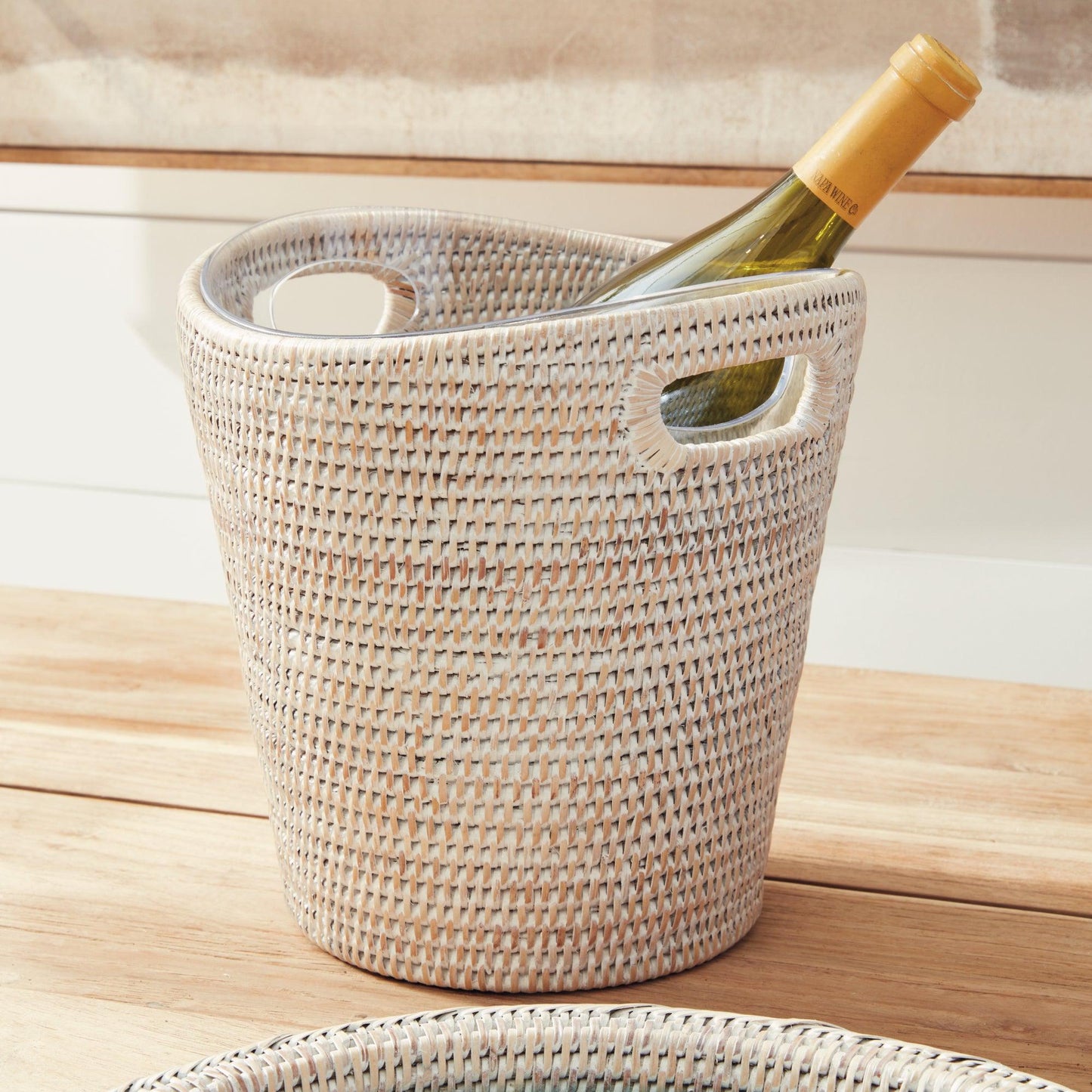 Rattan ice bucket with bottle of wine on wood table
