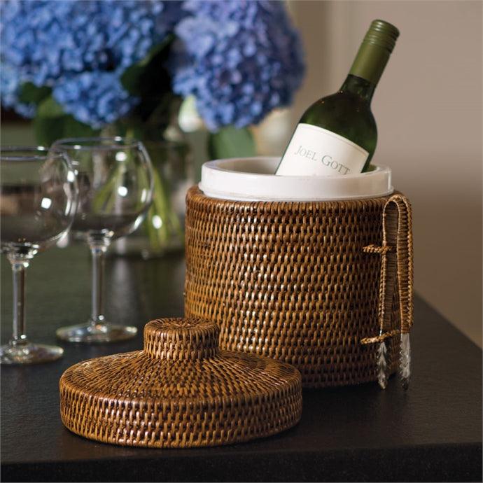 a bottle of wine sitting in a wicker basket next to a glass of wine