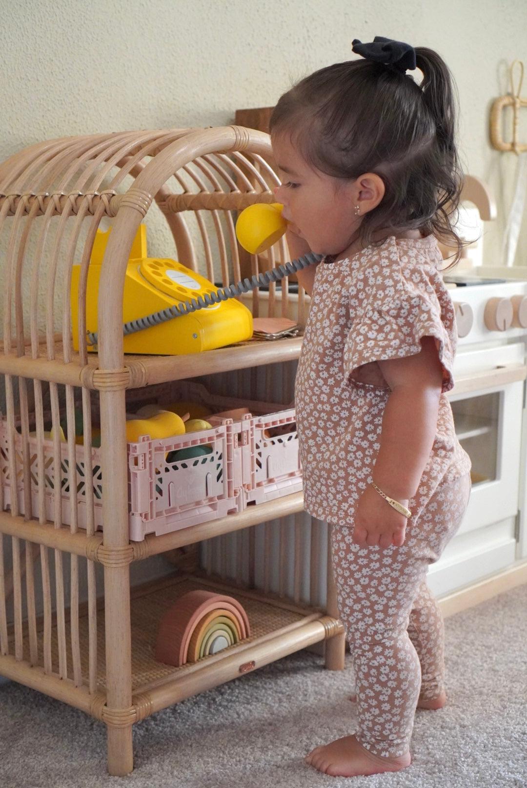 child in front of rattan childrens bookshelf
