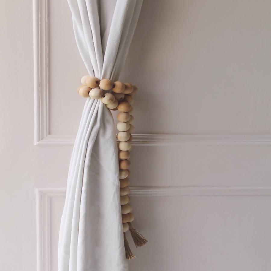 a curtain hanging on the side of a door with wood bead tie