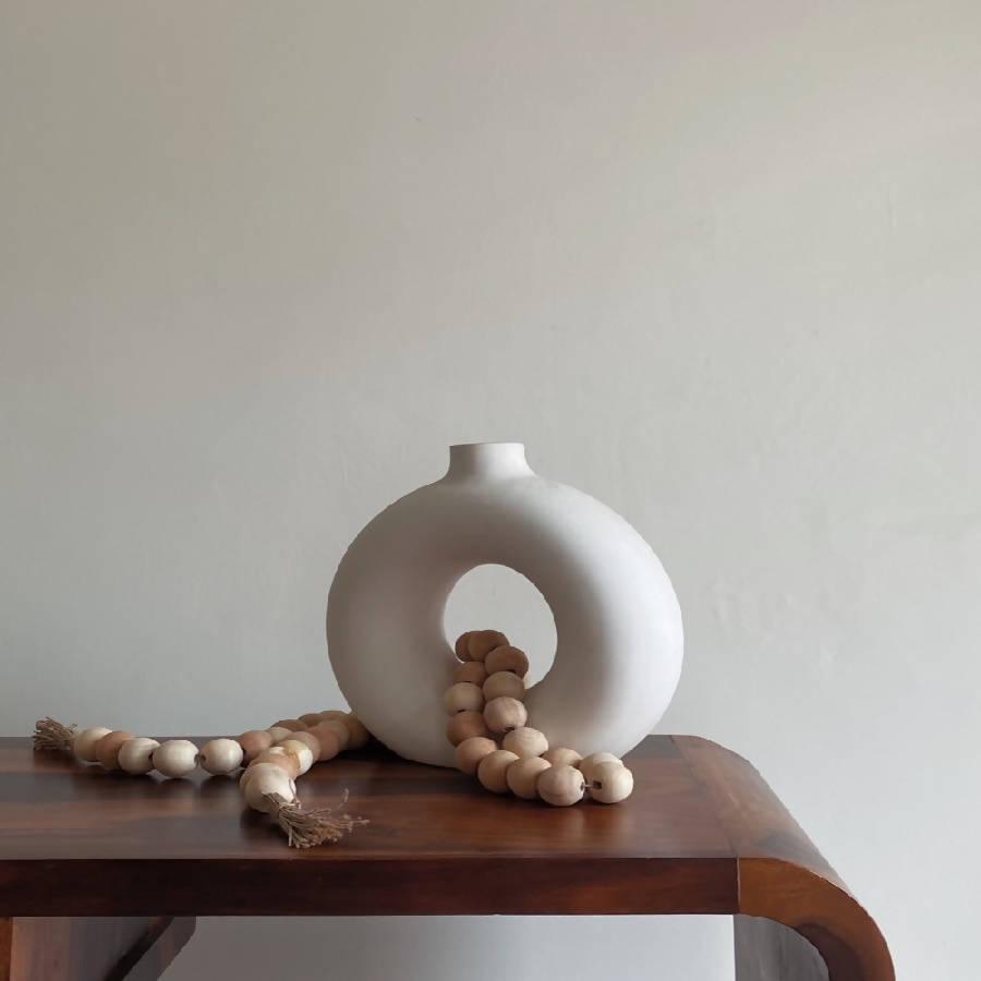 a white vase sitting on top of a wooden table