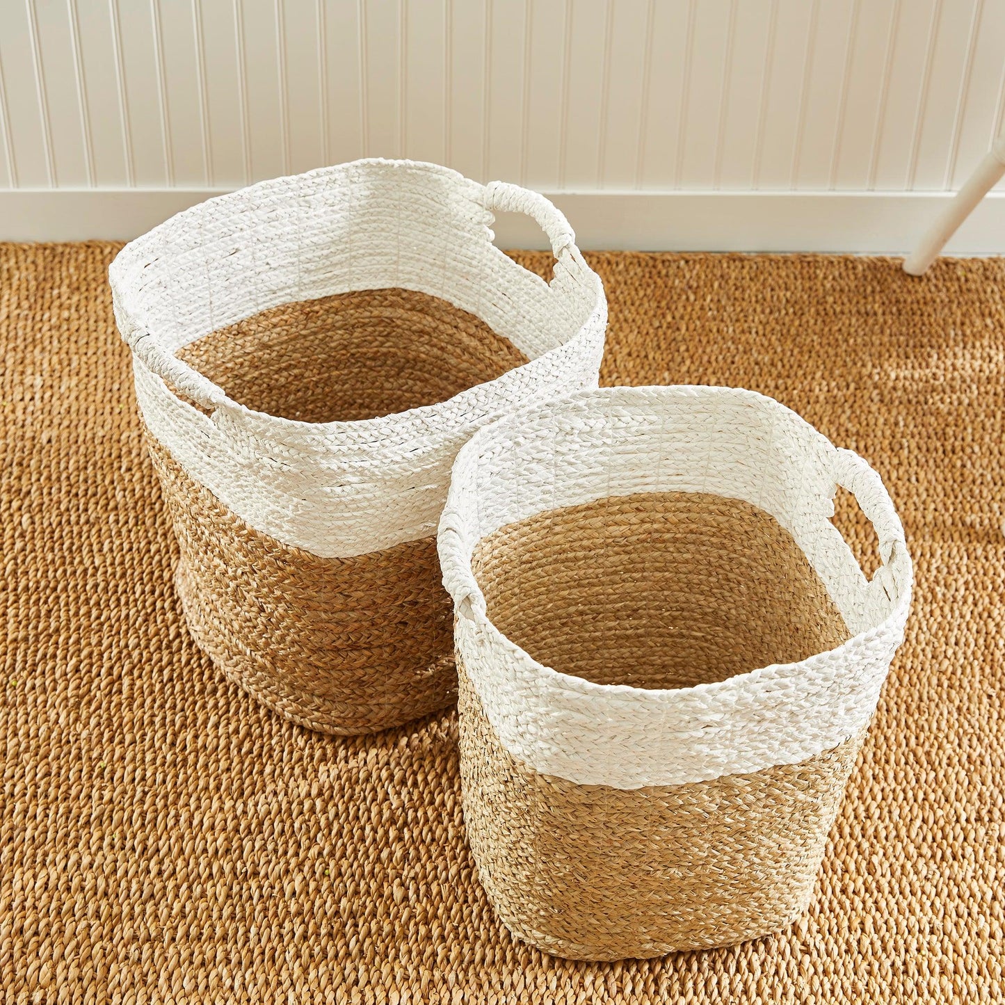 two woven baskets sitting on top of a rug