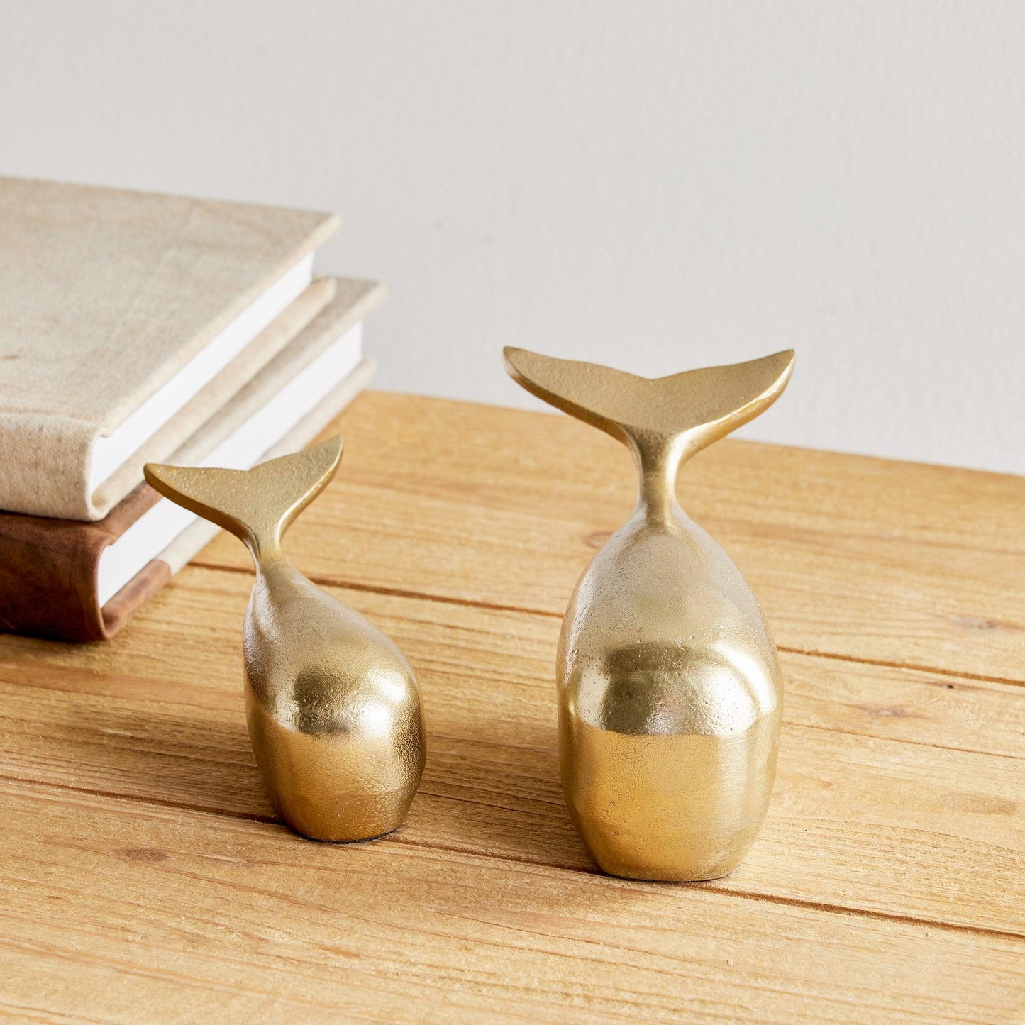 a couple of gold whales sitting on top of a wooden table