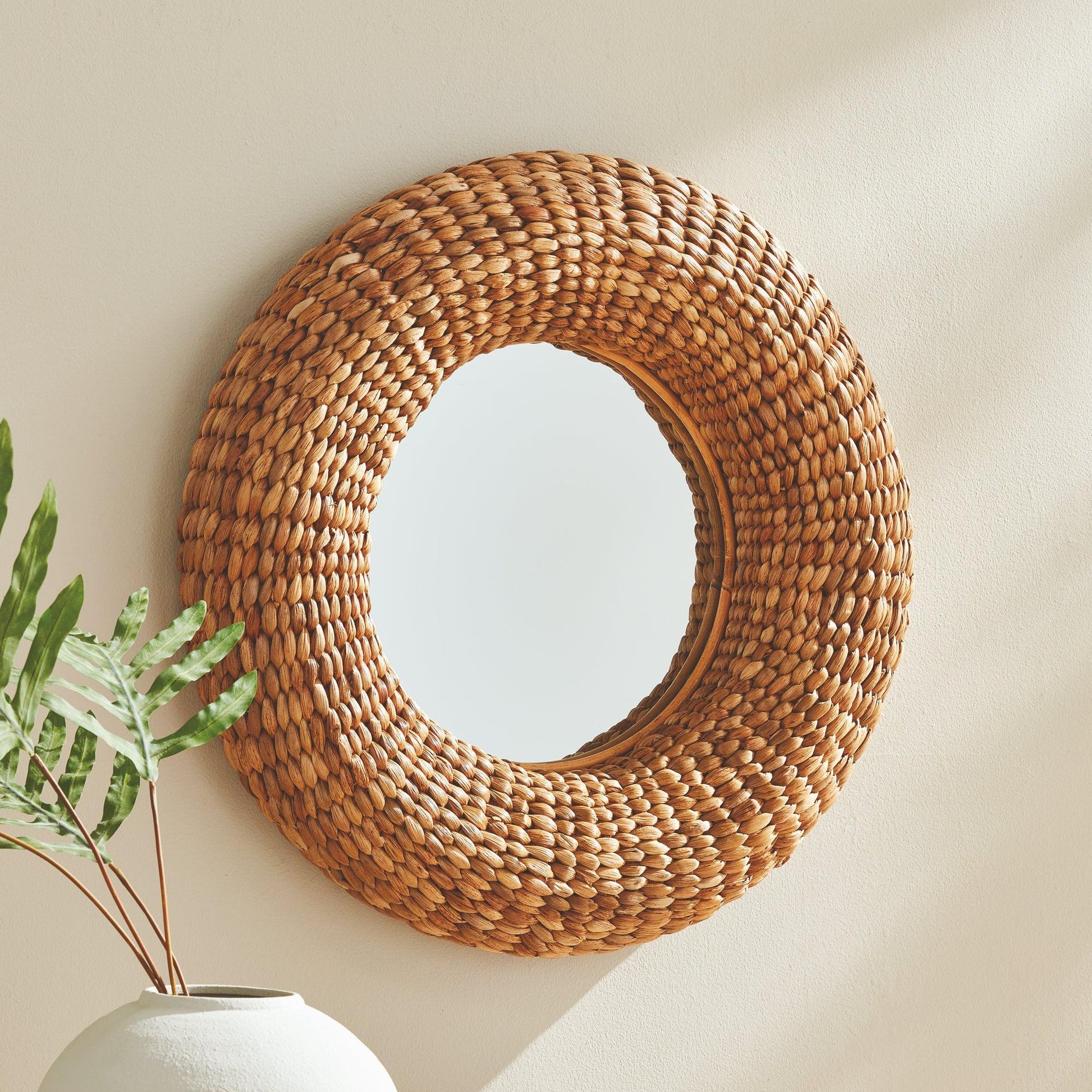 round woven mirror next to a plant
