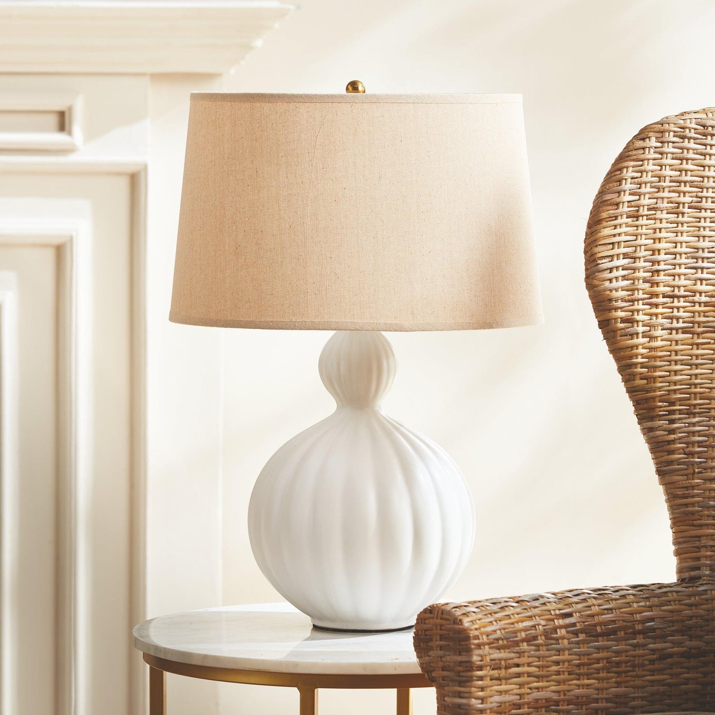 white lamp on a table next to a wicker chair