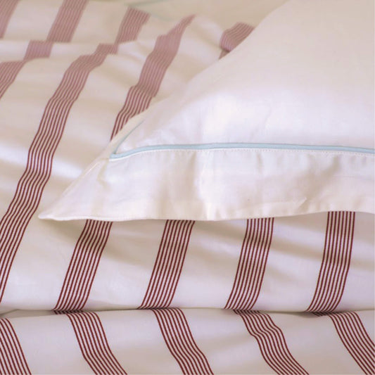 Rimini cotton sateen sham layered on striped coastal bedding — summer to fall bedroom transition