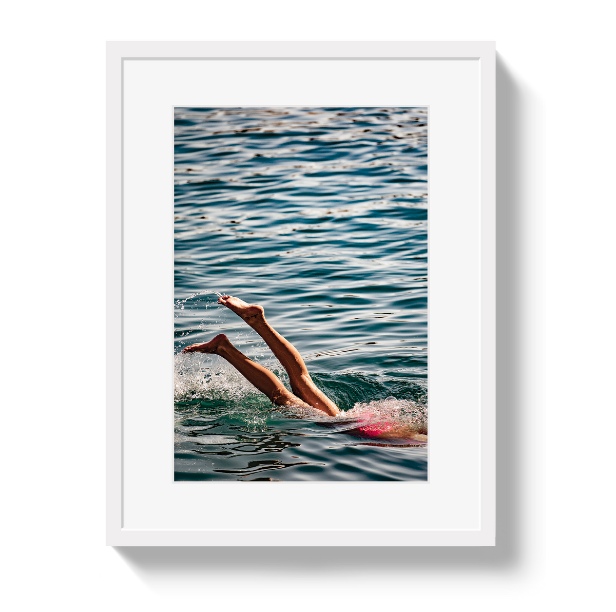 Joy Of Life swimmer photograph in a white frame with a white border, showing raised legs above blue-green water