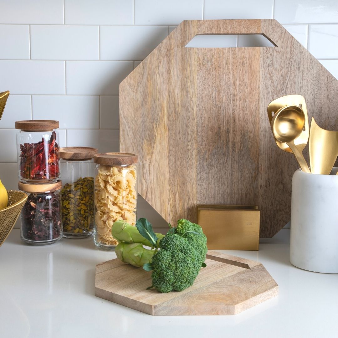 Leo mango wood boards in two sizes with cutout handles and a gold-colored stand, styled on a kitchen counter