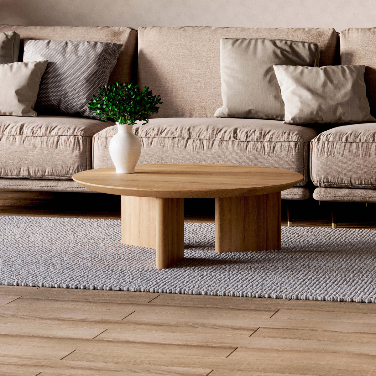 Noah round oak coffee table styled with a white vase in front of a beige sofa