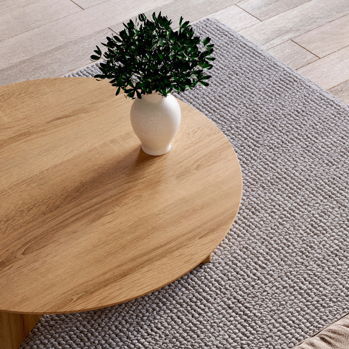 Close-up of the Noah oak tabletop with visible wood grain and a white vase of greenery