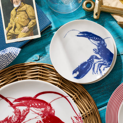 	Blue lobster appetizer plate on a turquoise wooden table beside red lobster tableware and a woven charger