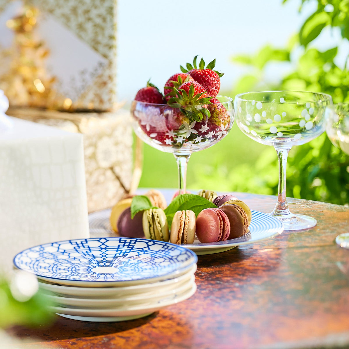 Stack of Newport blue-and-white small plates on a dessert table with macarons and strawberries