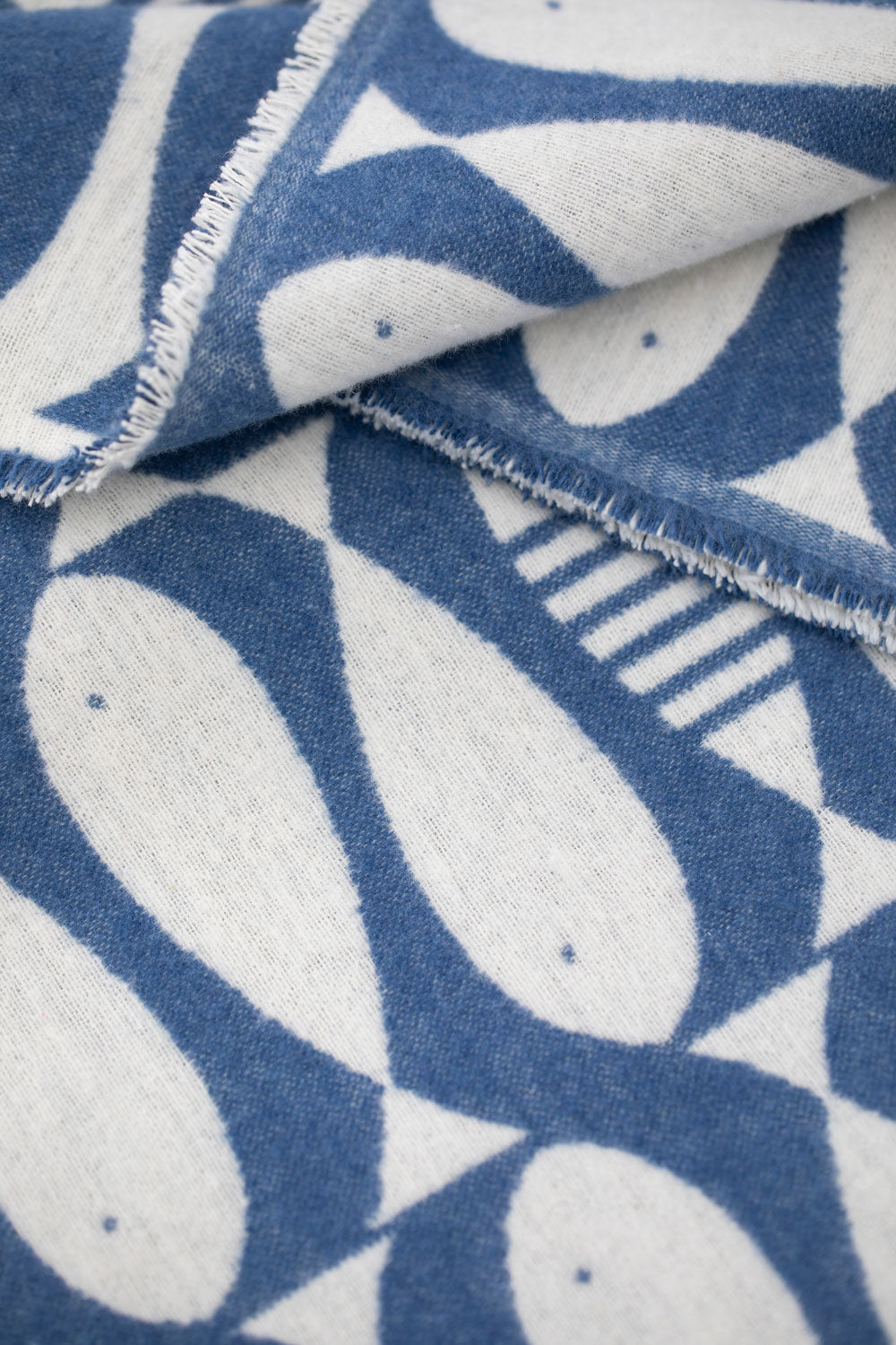 Close-up of the LUCA Sardines throw showing its navy and cream fish pattern and softly frayed edge