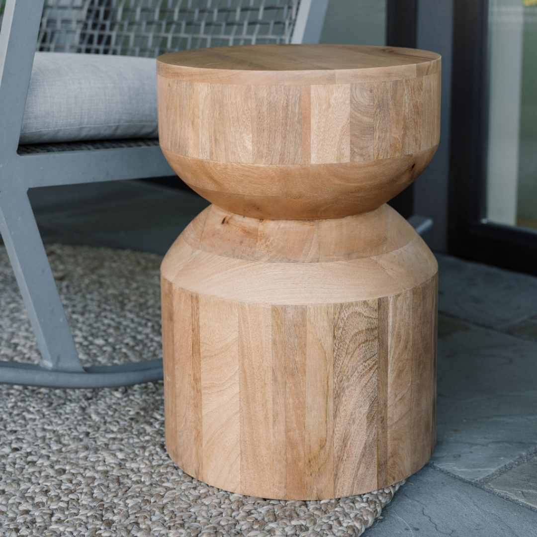 Natural jute rug styled beneath a sculptural wooden side table beside a woven chair
