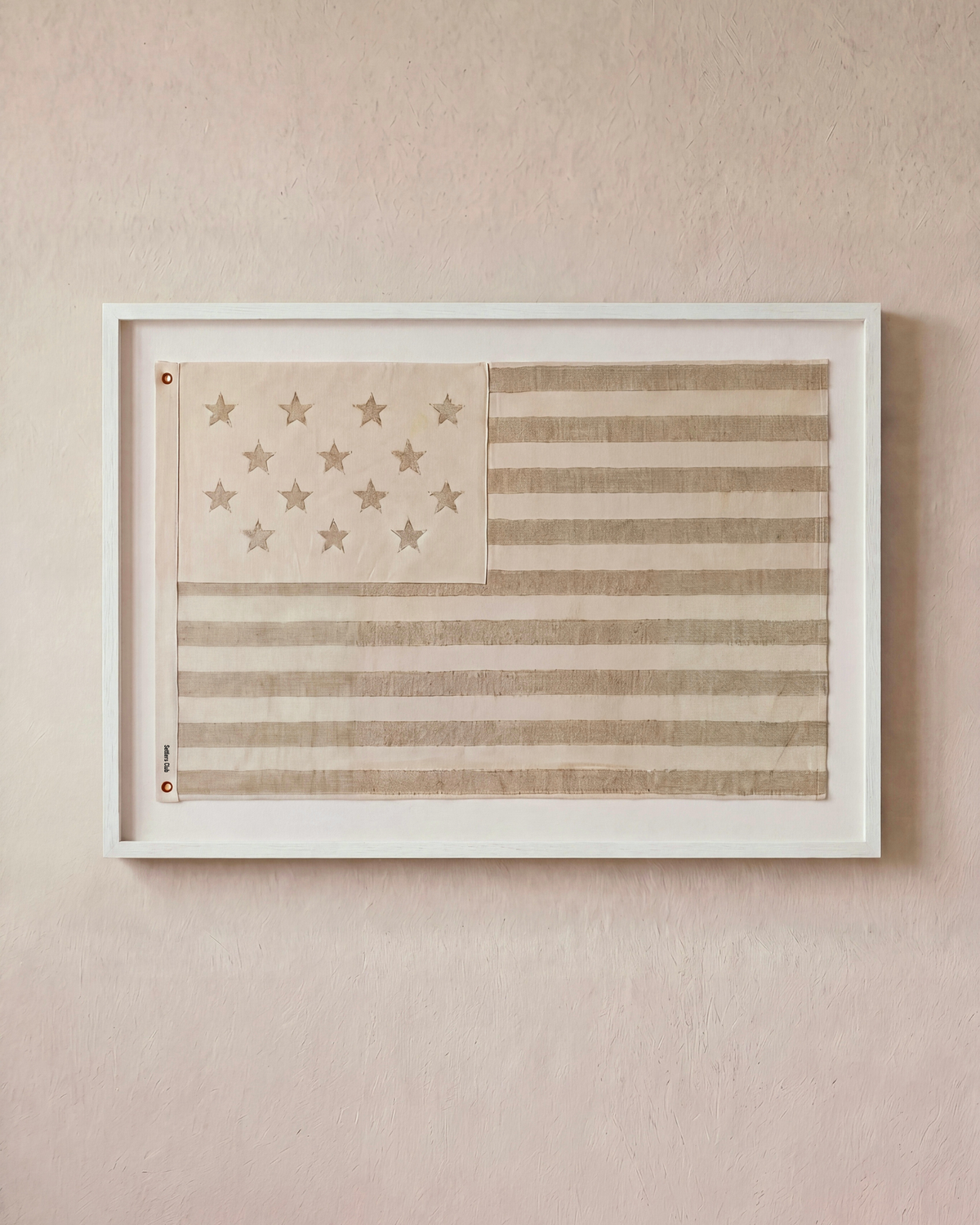 Sand-toned embroidered American flag displayed horizontally in a white shadowbox frame.