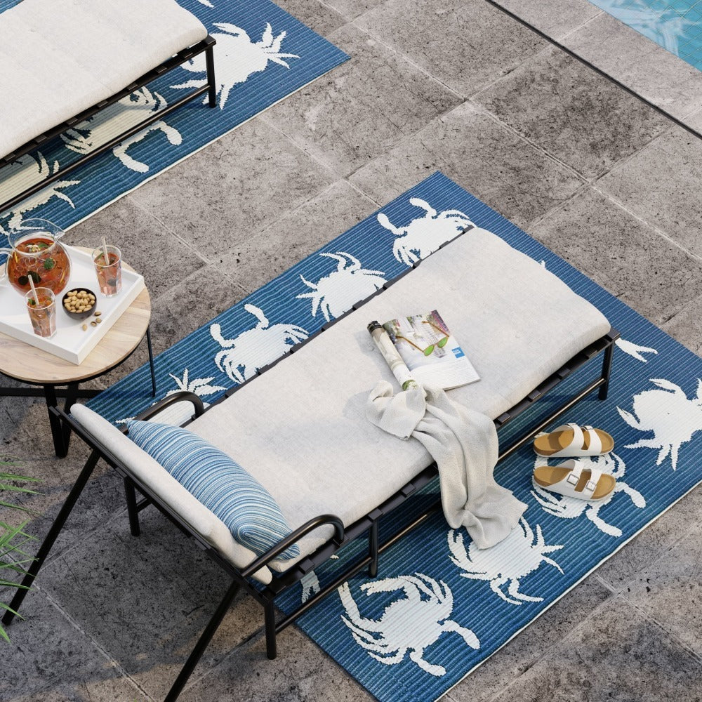 Blue crab-pattern outdoor rug beneath a white-cushioned poolside lounge chair