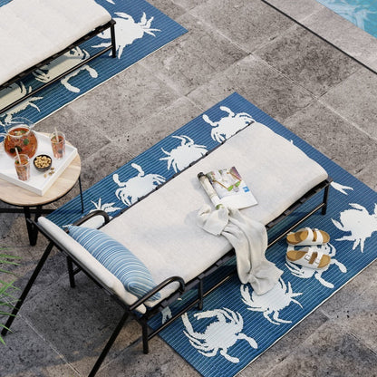 Blue crab-pattern outdoor rug beneath a white-cushioned poolside lounge chair