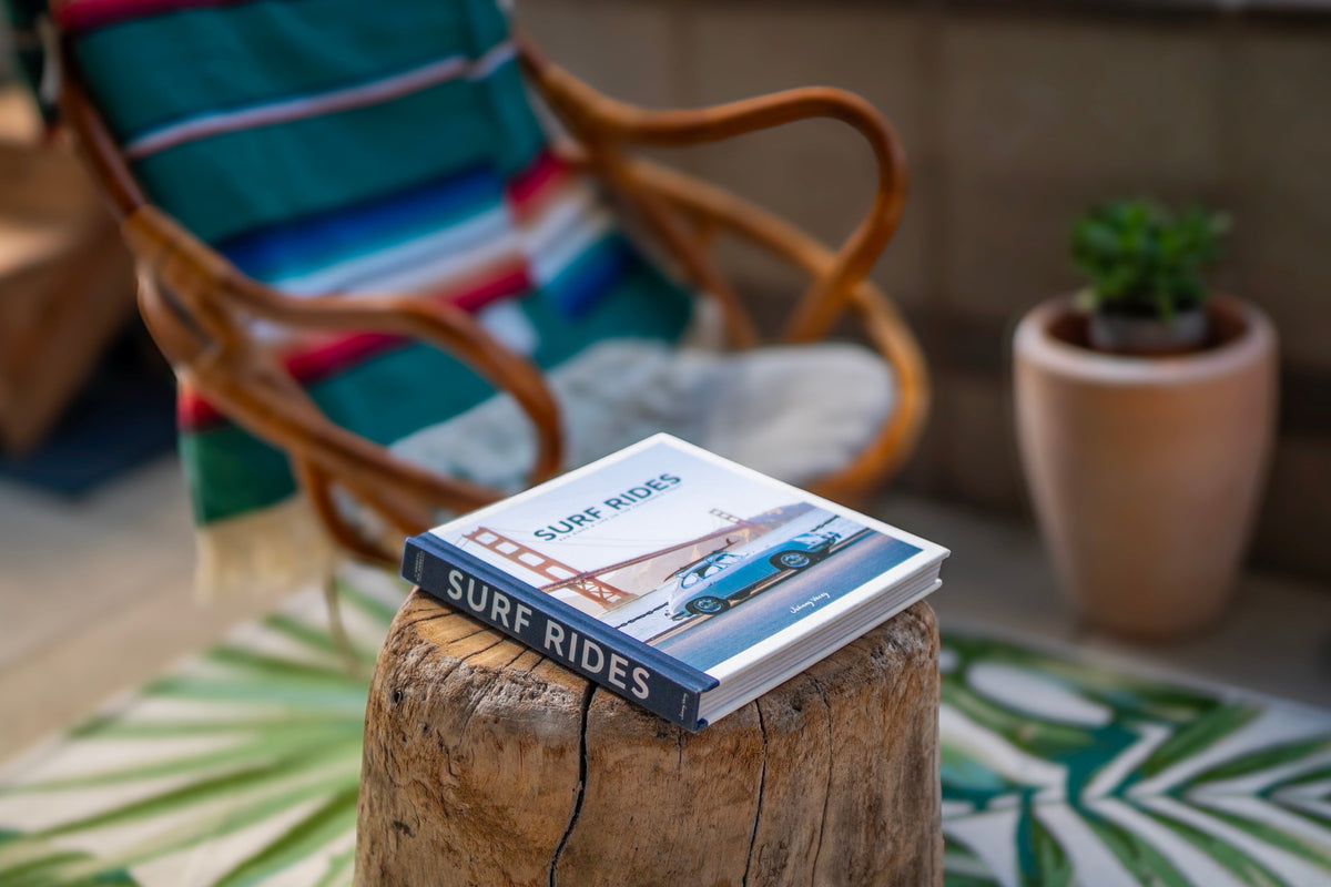 Surf Rides book styled on a wood stump table beside a woven chair