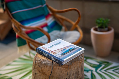 Surf Rides book styled on a wood stump table beside a woven chair