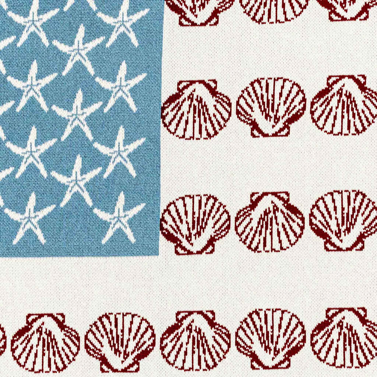 Close-up of the Coastal Flag blanket’s knit texture, white starfish, and red seashell motifs