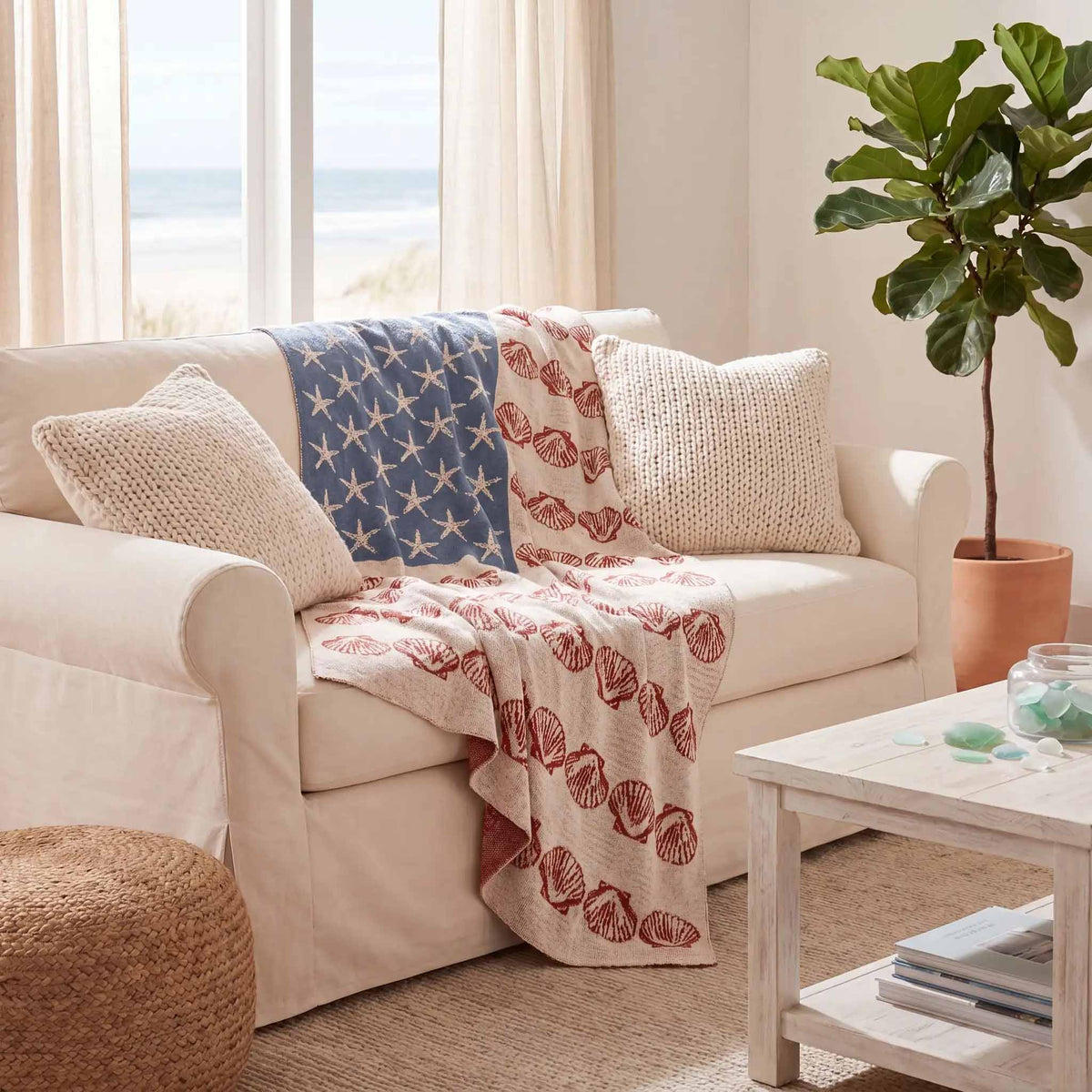 	Coastal Flag starfish and seashell blanket draped across a white sofa beside a sunny window