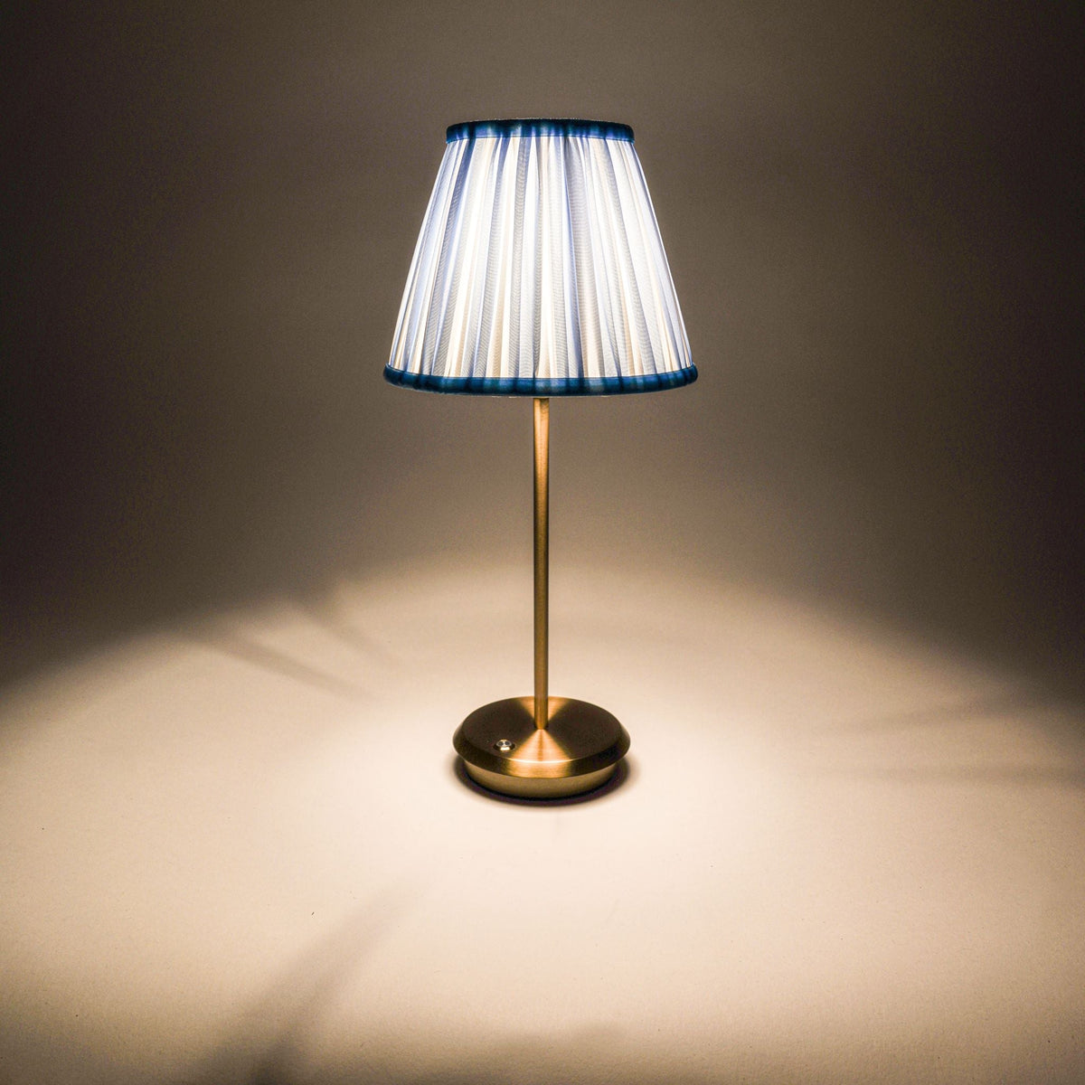 	Illuminated Blue Velvet Tides cordless lamp casting light through its striped shade