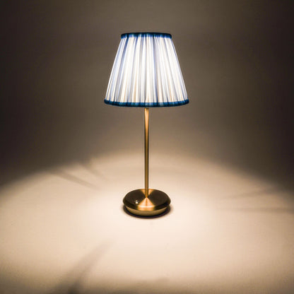 	Illuminated Blue Velvet Tides cordless lamp casting light through its striped shade