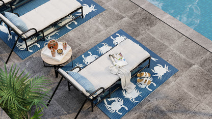 Angled poolside view of the blue crab-pattern rug beneath a lounge chair beside a small table
