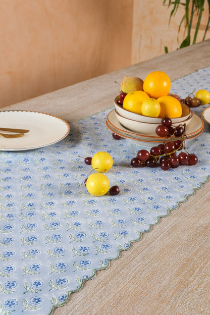 Close-up of the Mona runner’s blue floral blockprint and green embroidered scalloped border beside a fruit bowl.