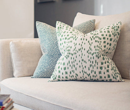 	Java Java Navy geometric pillow layered behind a green-and-white patterned pillow on a light sofa