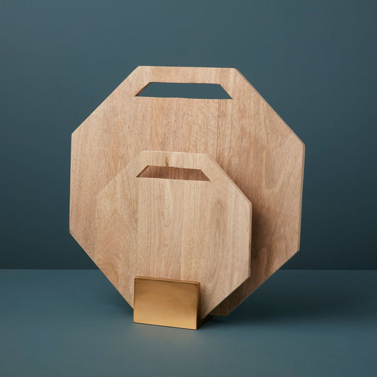 Two geometric Leo mango wood serving boards displayed upright in their gold-colored storage stand