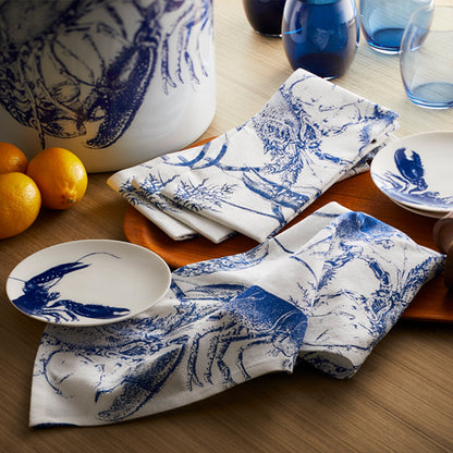 	Blue lobster small plates styled with matching patterned napkins, blue glasses, lemons, and a large decorative vessel