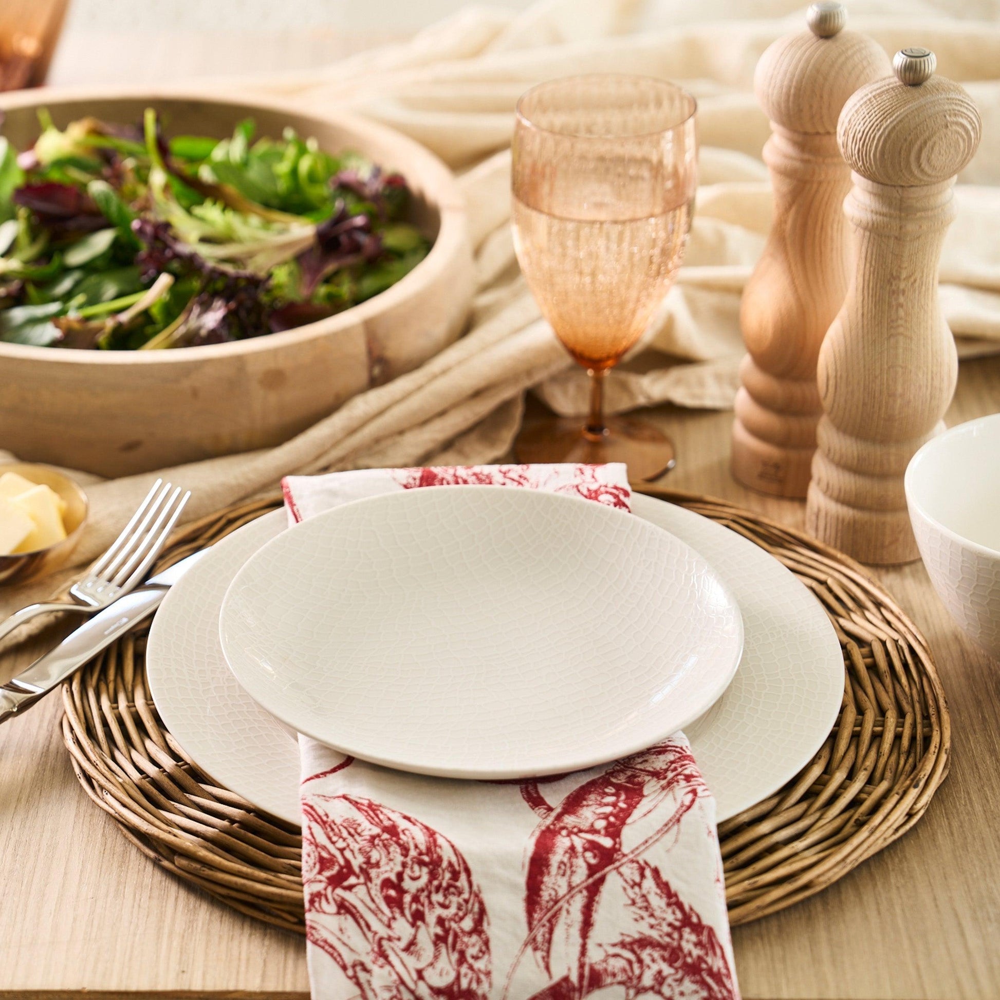 a table with a bowl of salad and a plate with a napkin on it