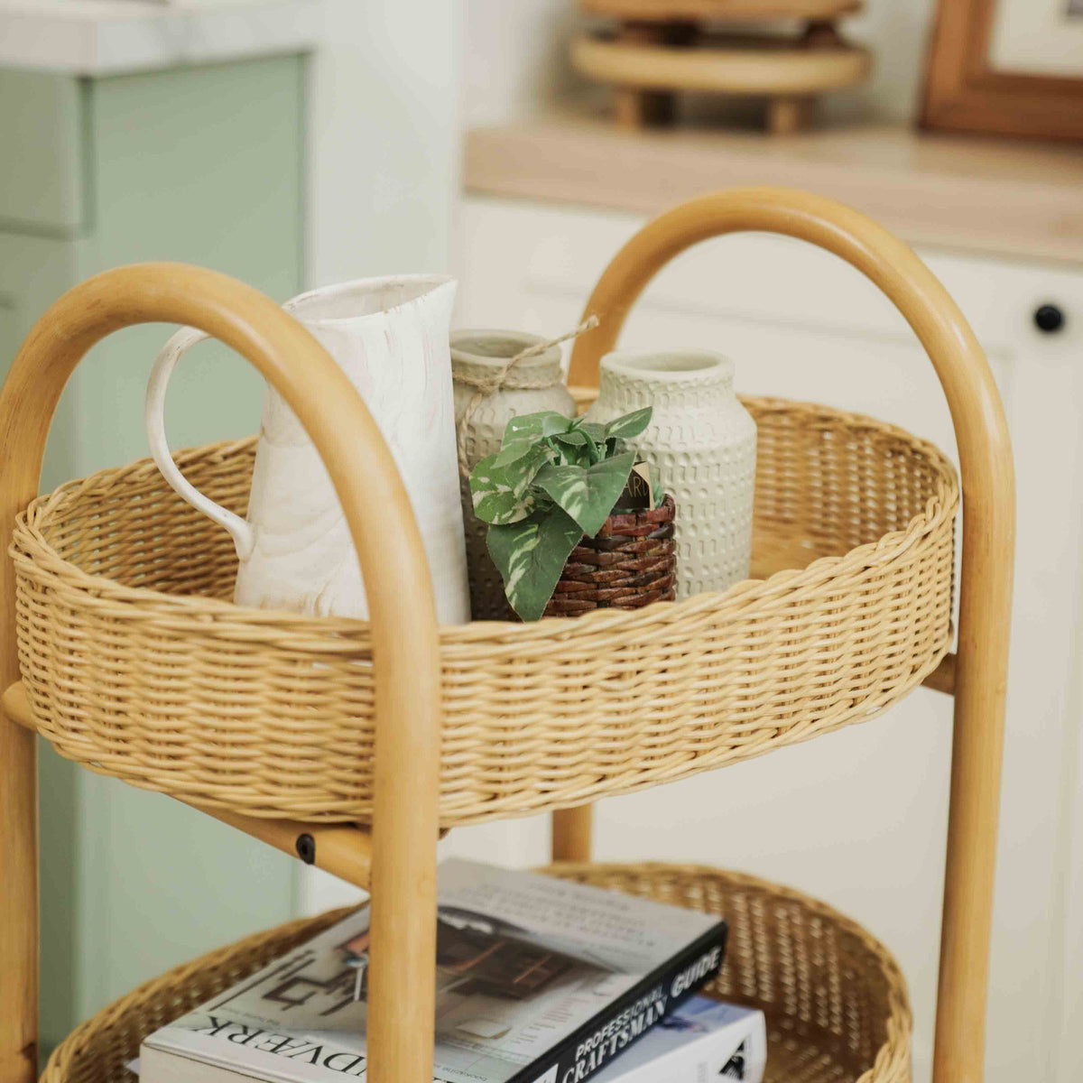 	Close-up of the trolley’s woven top basket and curved rattan handles with pitchers and a small plant