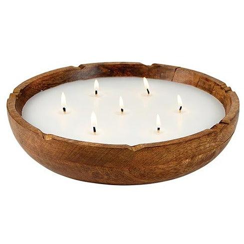 a wooden bowl filled with white candles