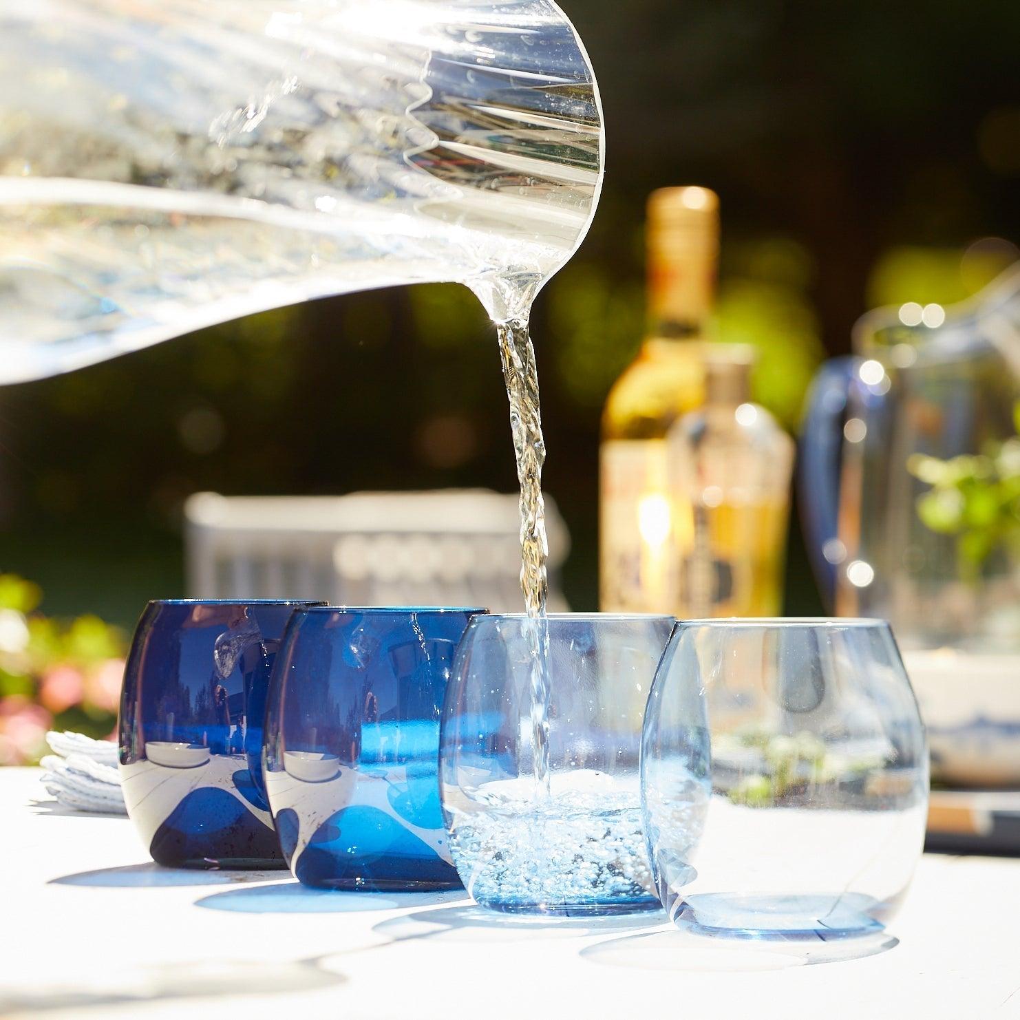 a pitcher pouring water into three glasses