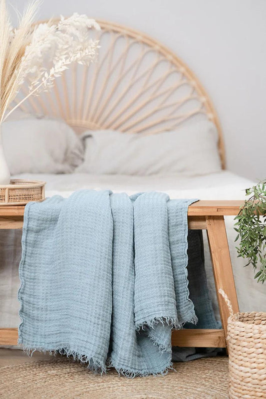 a bed with a wicker headboard and a blue blanket