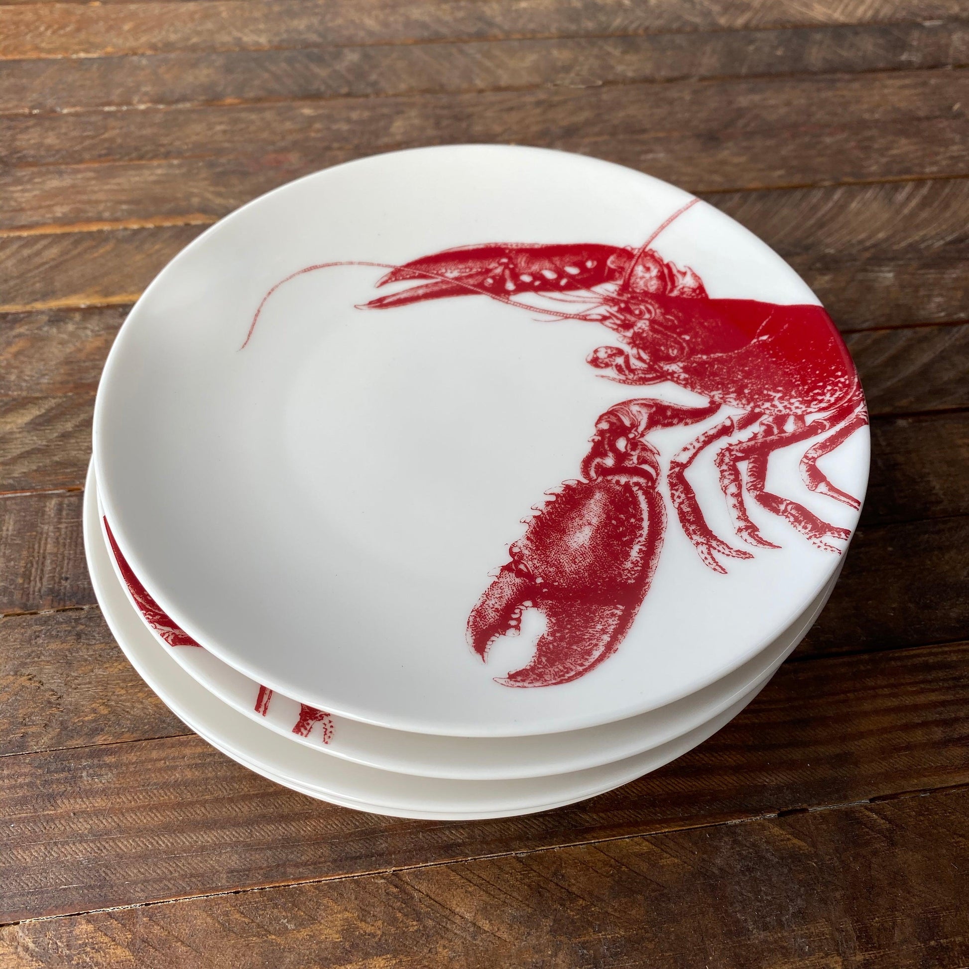 a stack of three plates with a red lobster on them