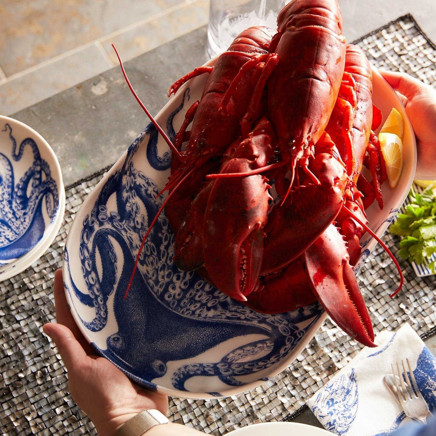 a person holding a plate of cooked lobster