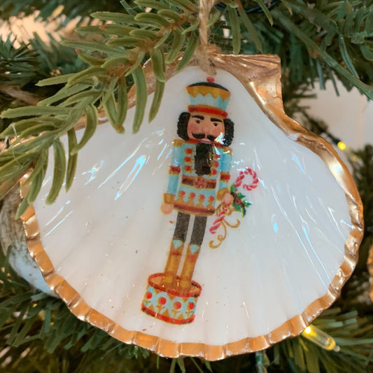 gold and white shell with painted nutcracker on a pine tree